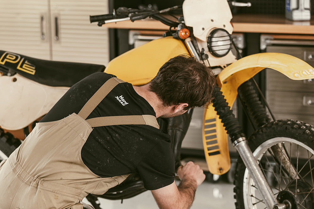 Person working on a yellow motorcycle in a garage