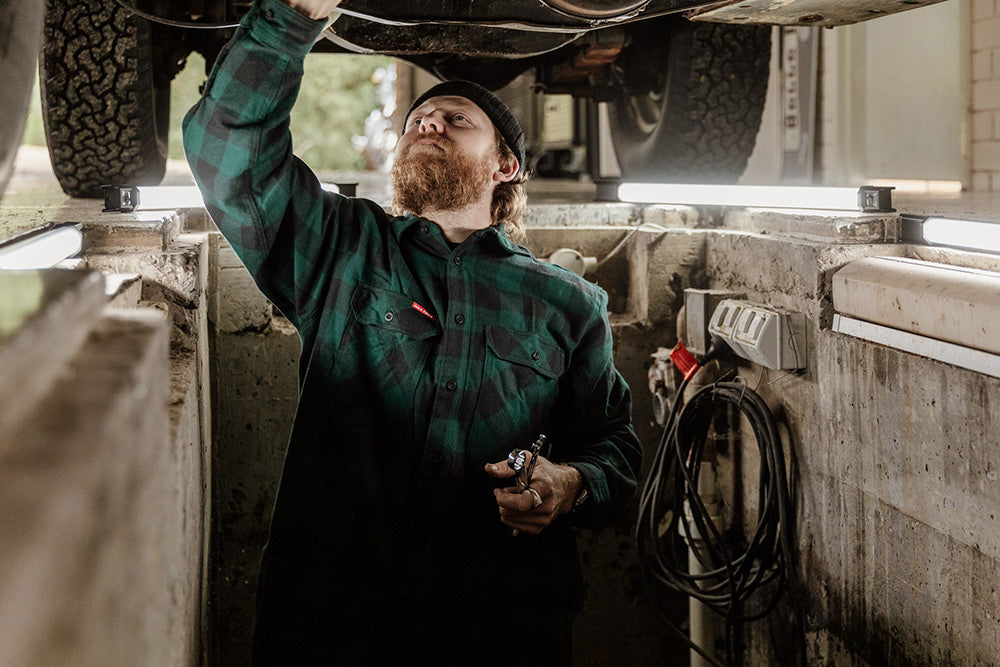 Man working on a vehicle undercarriage in a garage.