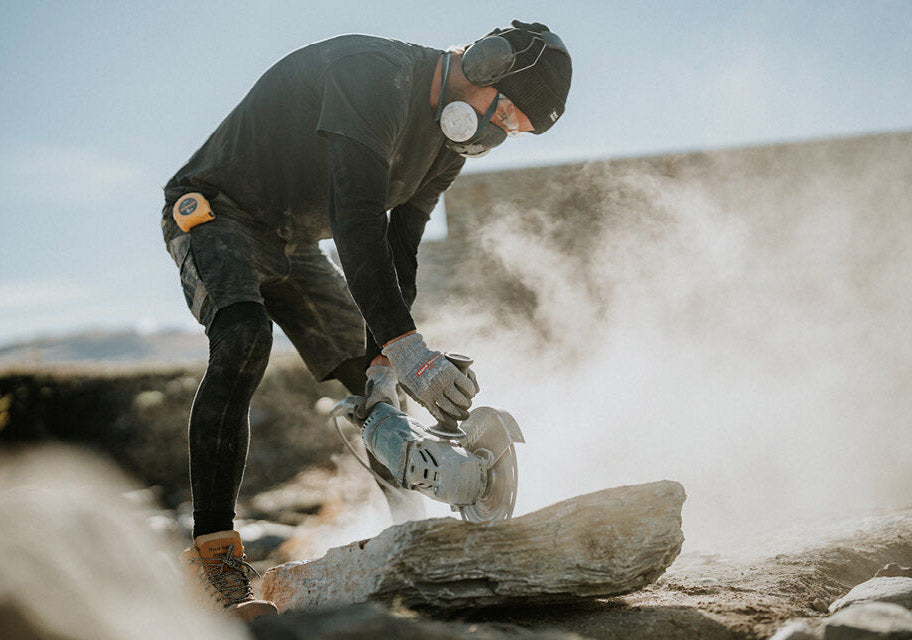 Person using a chainsaw to cut through a log outdoors
