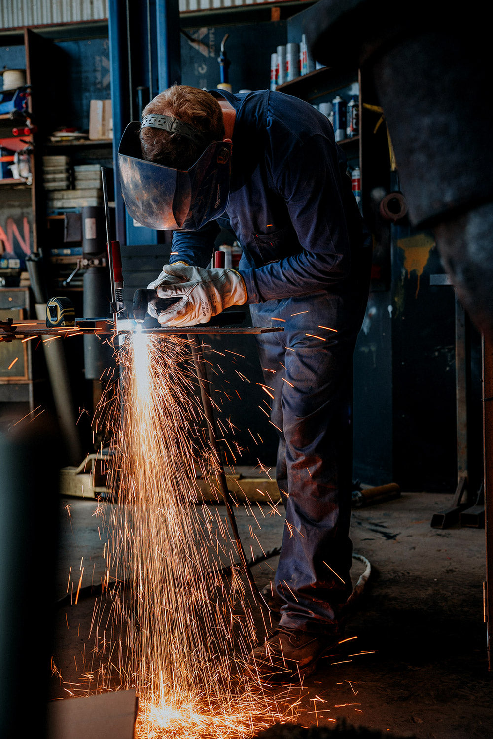 Worker welding metal with sparks flying in a workshop setting