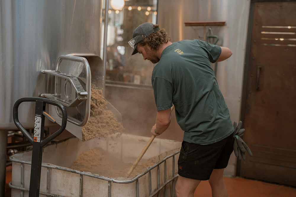 Person working with grain in a brewery setting