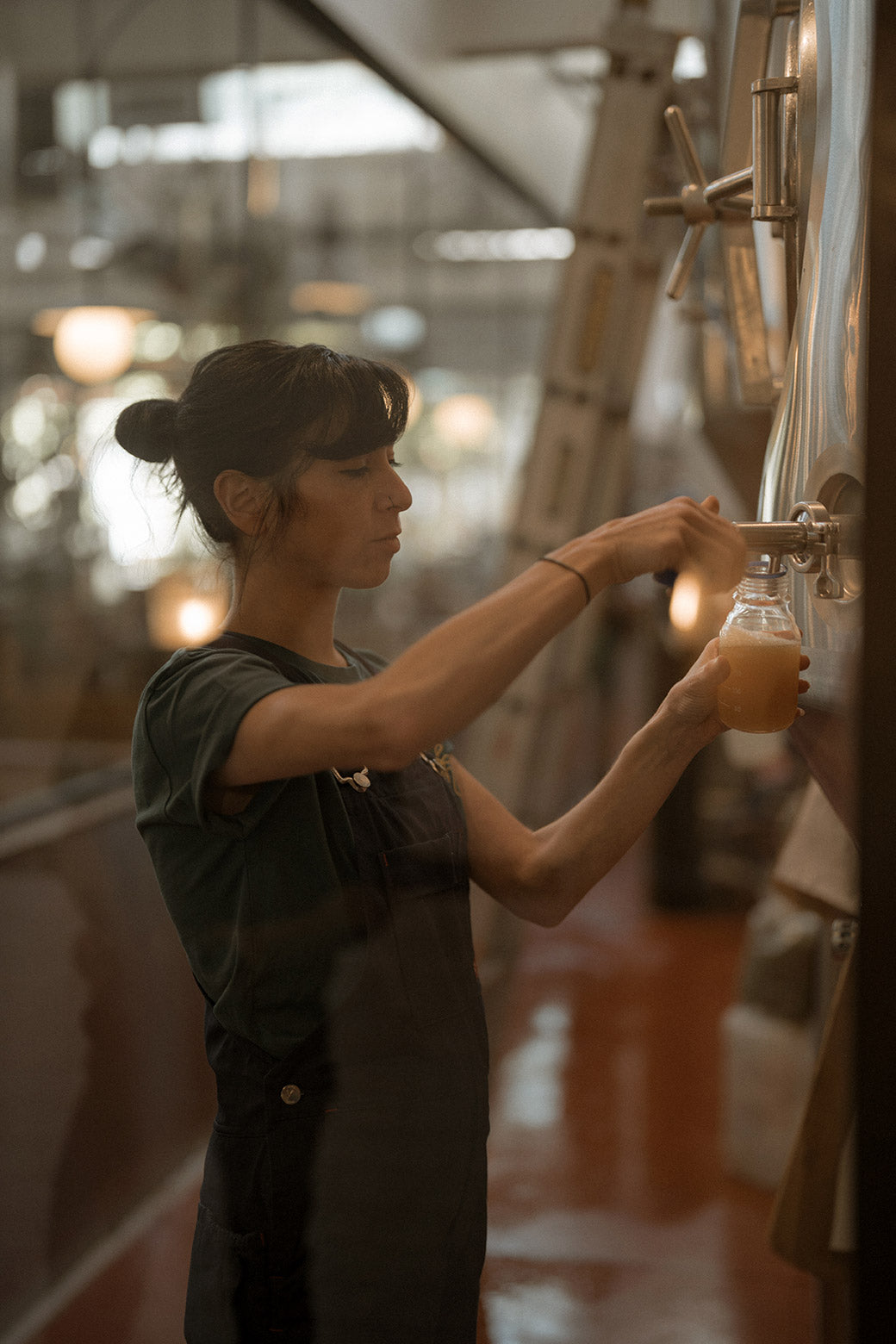 Person pouring a drink from a tap into a glass.