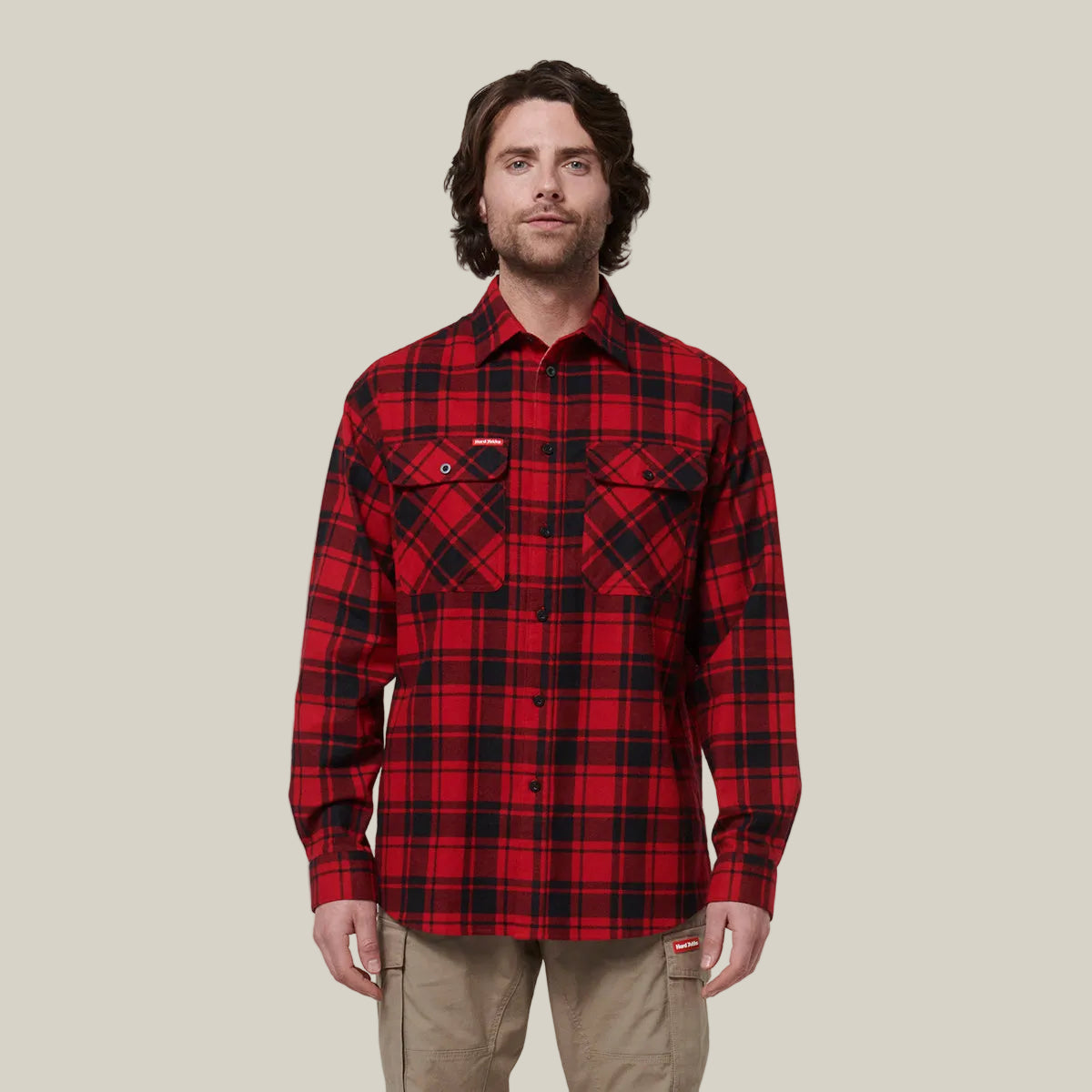 Man wearing a red and black plaid shirt against a plain background