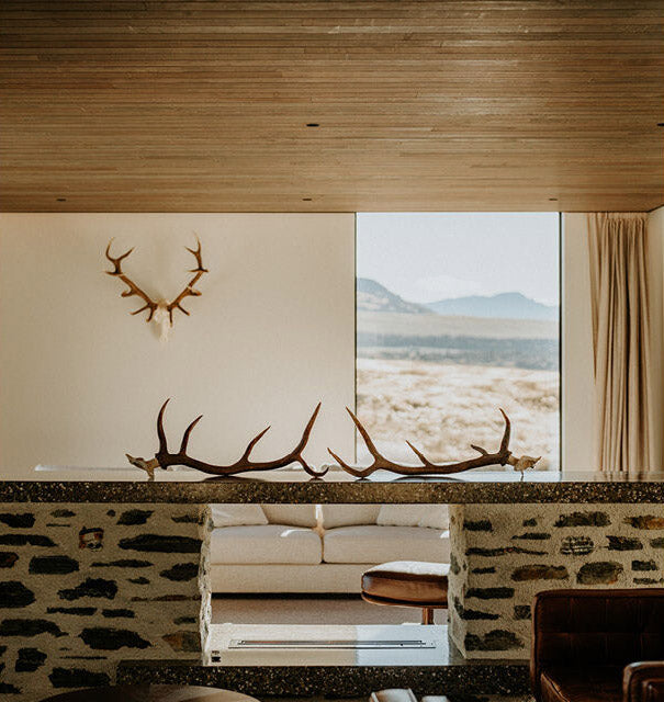Modern living room with stone wall, white sofa, and large window view of mountains.