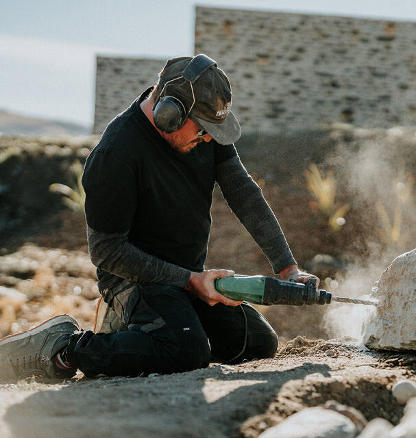 Person using a jackhammer on a stone surface with a blurred background