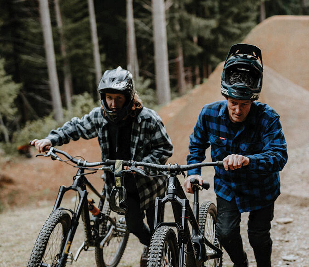 Two mountain bikers on a trail with trees in the background