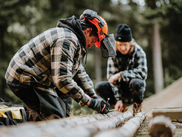 Two men working with wood in a forest setting