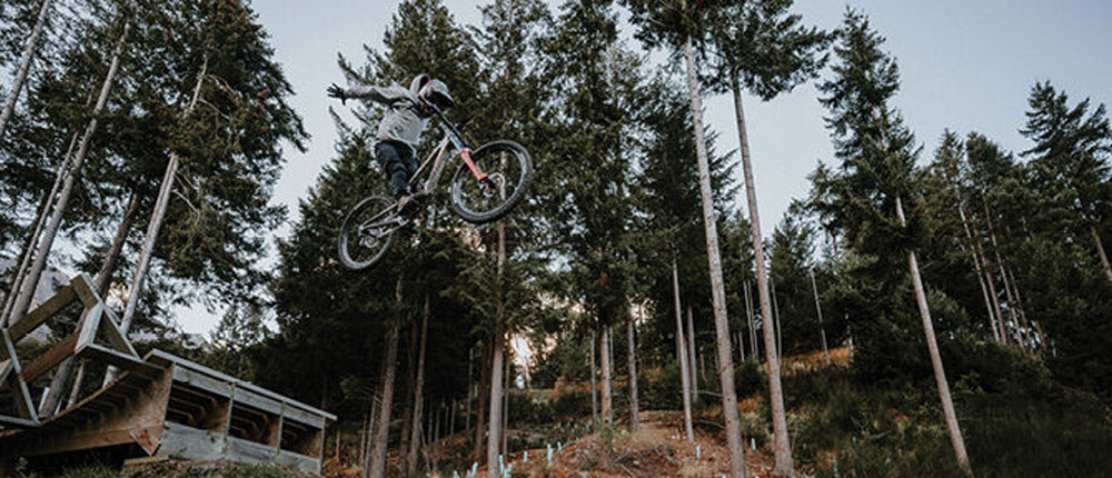 Person on a bicycle performing a jump in a forest setting