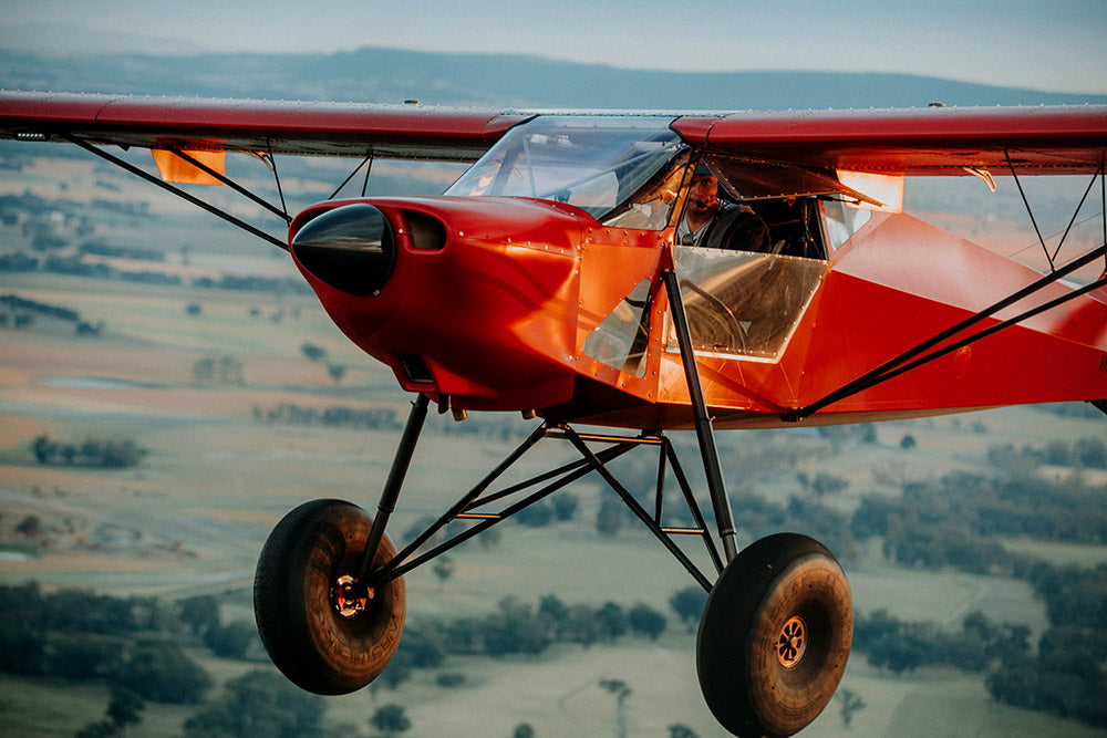 Red biplane flying over a landscape